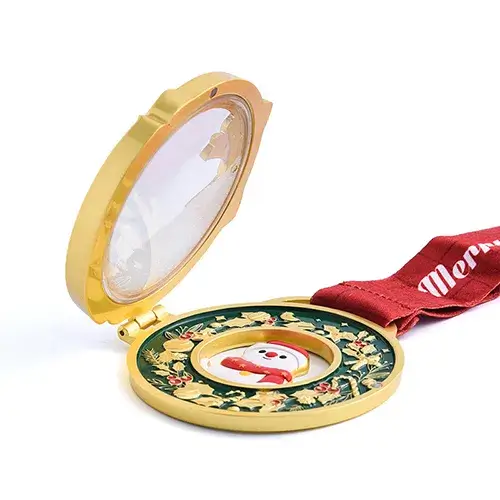 Gold-tone Christmas medal with a hinged cover, featuring a snowman in the center and a festive holly design around the border.