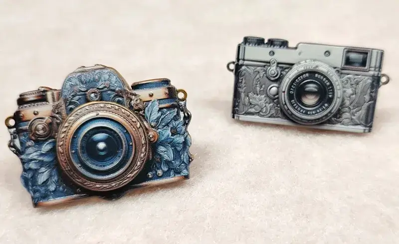 Két vintage kamera alakú hajtókatű UV nyomtatott textúrákkal, realisztikus felületi részletekkel és gravírozott effektekkel kiemelt fémfelületeken
